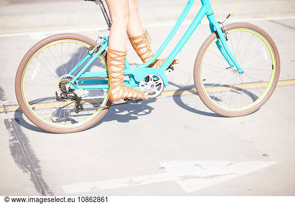 Legs and strappy sandals of young female cyclist at Venice Beach, Los Angeles, California, USA