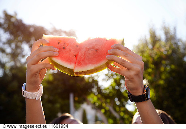 Teenage girls holding up watermelon in street