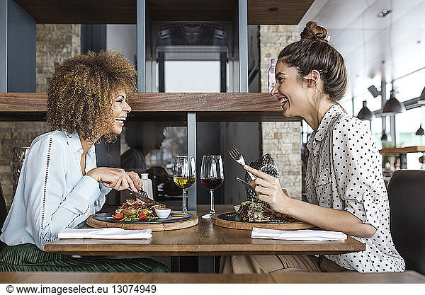 Cheerful businesswomen having lunch at table in restaurant