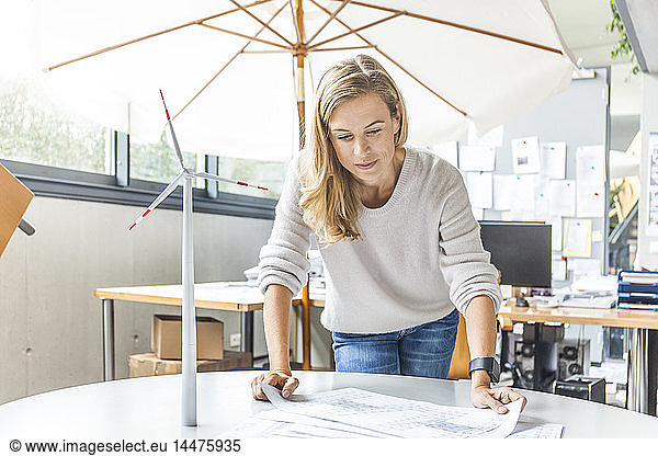 Woman in office working on plan with wind turbine model on table